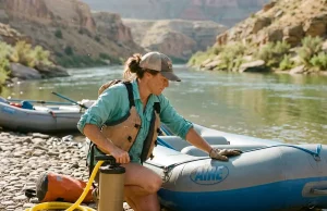 Why Your Raft Pressure Is Too Soft, Not Too Hard Boater airing up an AIRE raft at a desert river put-in, checking raft inflation pressure before launch