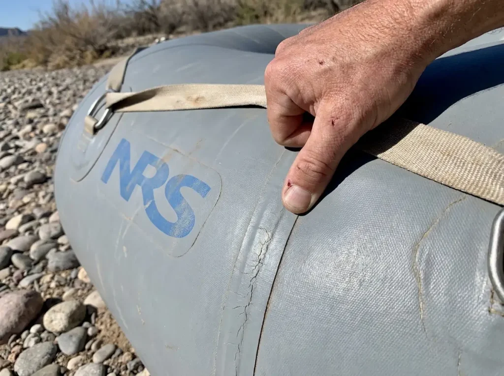 Thumb pressing a firm NRS raft tube to check 2.5 psi inflation pressure by feel