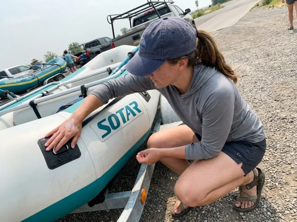 Boater checking a raft's build quality at the launch, judging warranty and expected raft lifespan