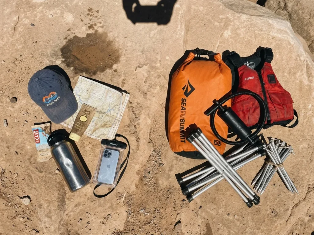 Rafting gear sorted on sandstone into quick-reach items and bulky under-seat gear before rigging