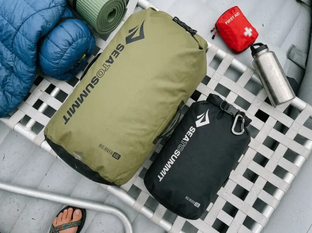 Two dry bags of different sizes laid out on a raft frame for a multi-day river trip