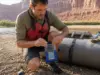 Rafting Electronics Explained by What Survives a Flip Rafter sealing a waterproof phone case on a raft tube before pushing off at the put-in