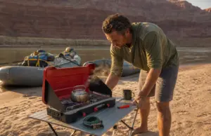 Best Camp Stoves for River Trips That Survive a Flip Two-burner camp stove set up on a river beach kitchen table in Grand Canyon at sunrise