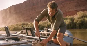 Best Water Jugs for River Trips That Survive a Flip Rafter strapping a Scepter water jug to a raft frame at a desert river put-in before a multi-day trip