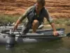 Drag Bags vs Soft Storage for River Camping Loaded mesh drag bag clipped to a raft D-ring, towing alongside the boat on a green desert river