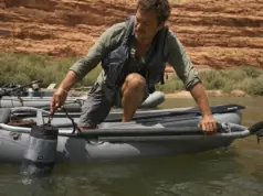 Drag Bags vs Soft Storage for River Camping Loaded mesh drag bag clipped to a raft D-ring, towing alongside the boat on a green desert river