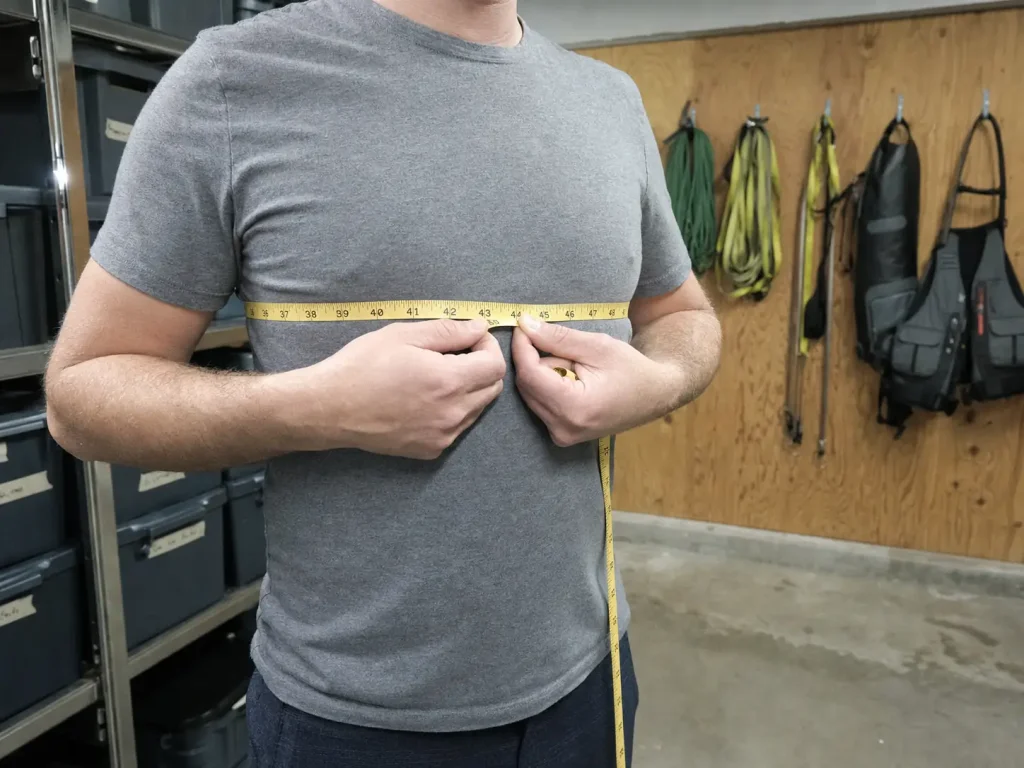 A person measuring their chest circumference with a soft cloth tape before buying a life jacket