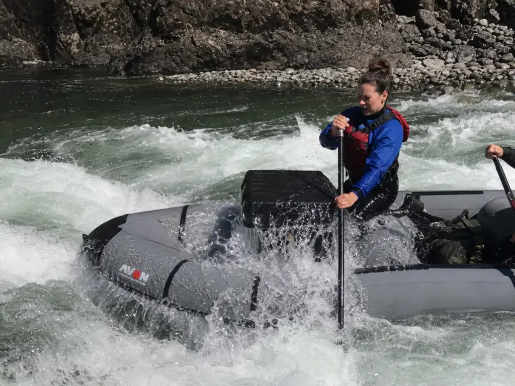 Raft punching through a hydraulic with whitewater breaking over the tube and gear