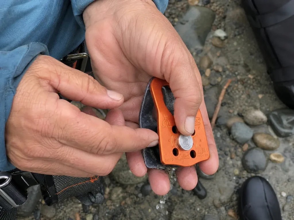 Rescue pulley sheave being spun by hand to check for grit after a season of sandy river put-ins