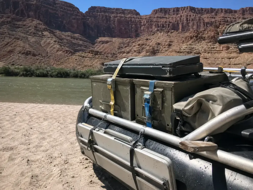 Camp kitchen gear strapped to a raft frame in rocket boxes on a Grand Canyon river beach