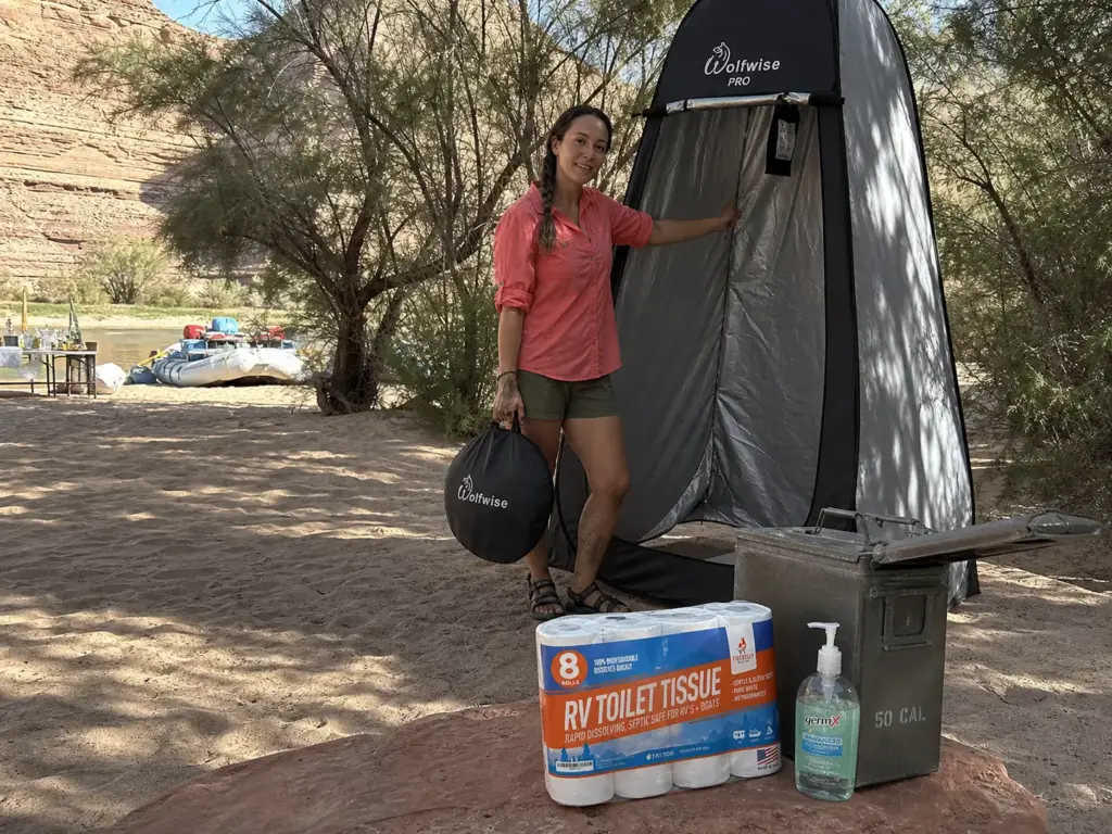 Pop-up privacy shelter set at the far end of a river camp beach with the groover key can nearby
