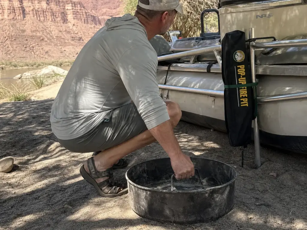 Heavy steel river fire pan and a folded lightweight pop-up pan side by side on a raft frame