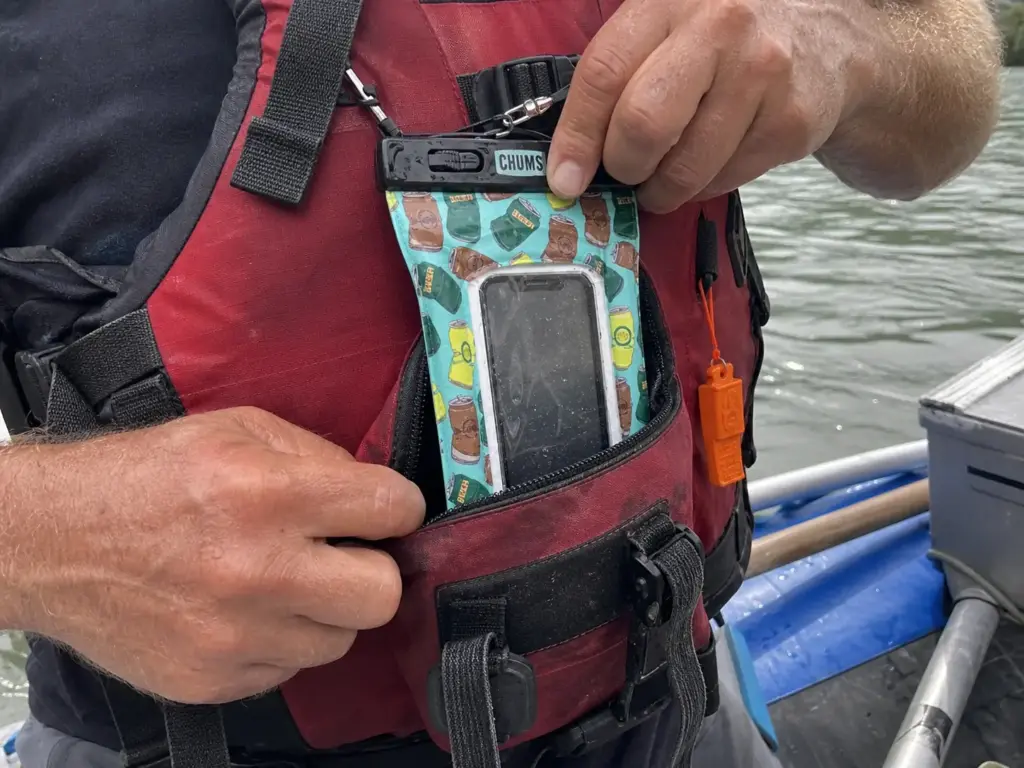 Floating phone case clipped and tethered inside a PFD front pocket on the river