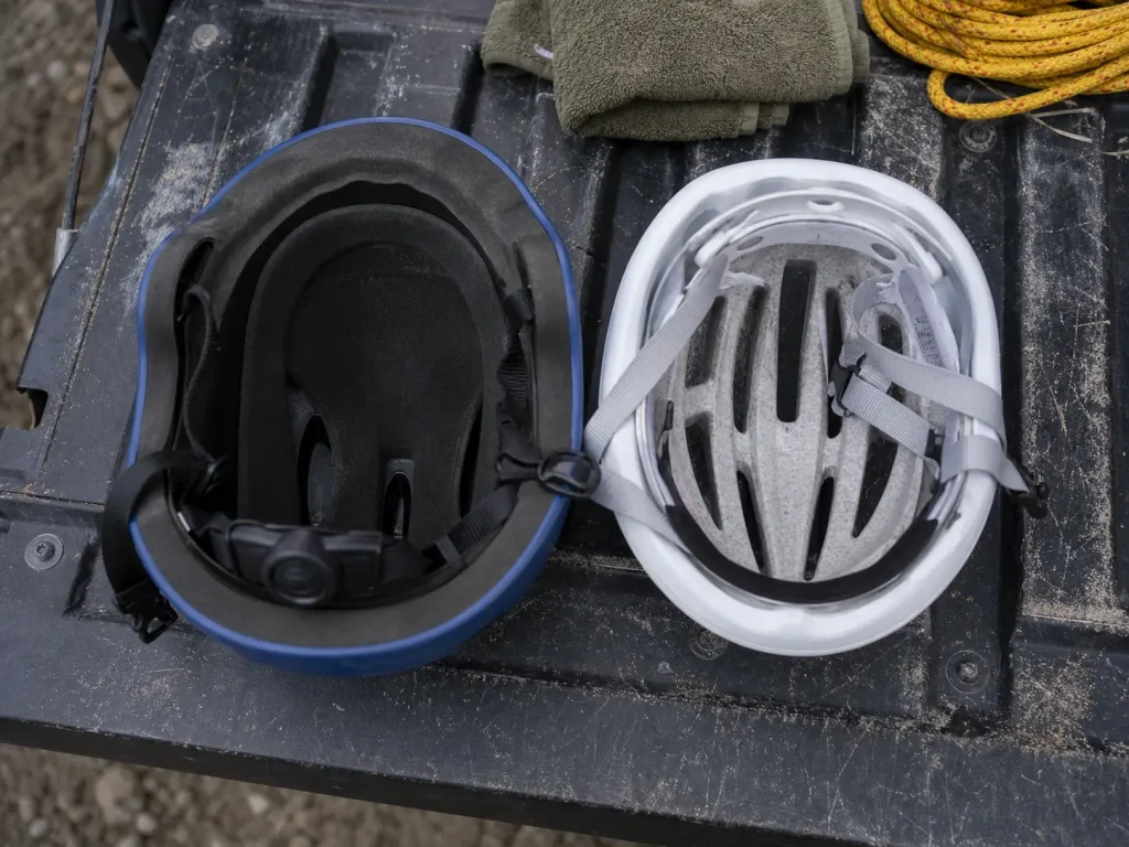 A whitewater helmet and a bike helmet side by side showing different liner foam