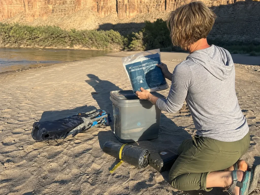 Packing a WAG bag waste kit into a river camping load on a Green River sandbar