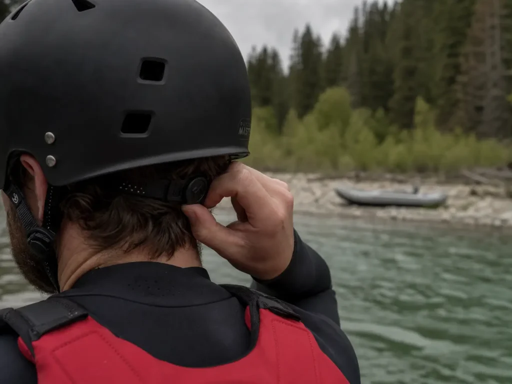 Rafter turning the rear adjustment dial on a whitewater helmet before launching