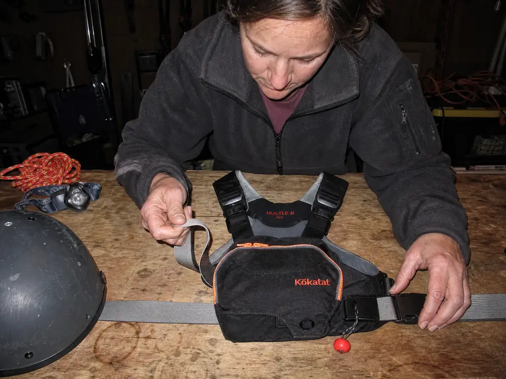 Inspecting the faded webbing and quick-release buckle of a rescue PFD in a dim garage