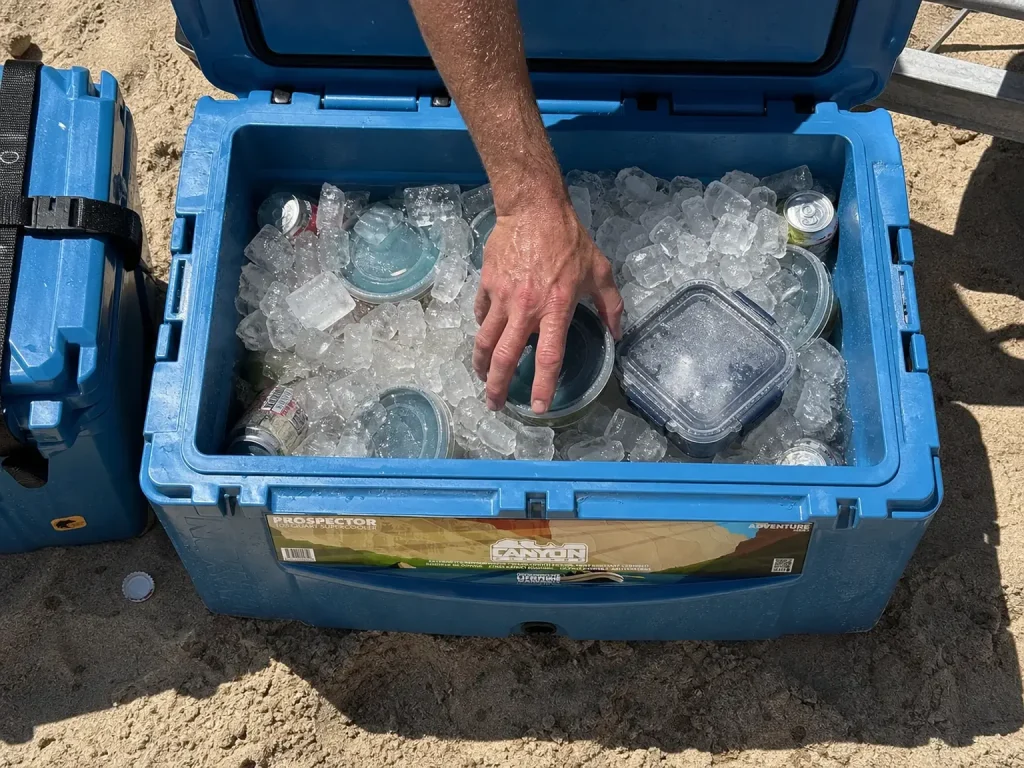 Open rotomolded cooler packed with ice at a two-to-one ratio on a river camping trip