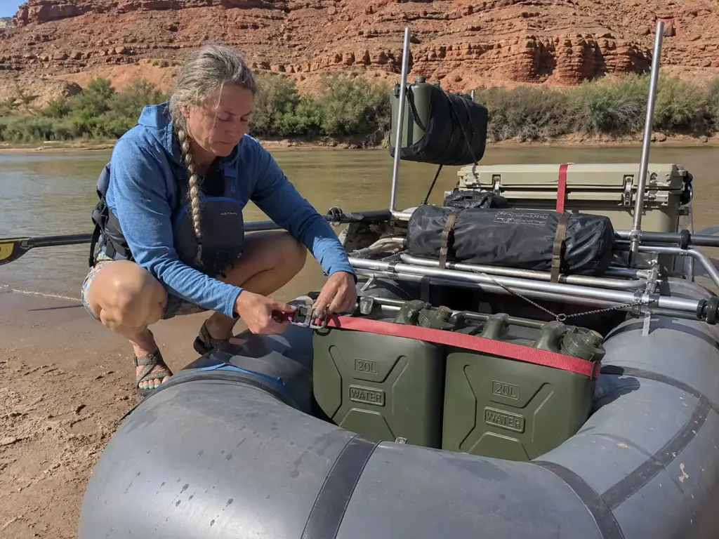 Green Scepter water jugs strapped behind the oar towers on a rigged raft frame at a Utah river camp