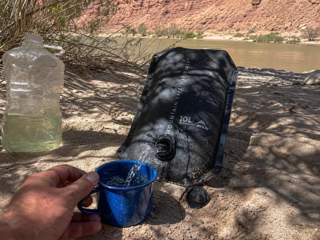 MSR Dromedary water bag in the shade at a desert river camp where deck sun heats stored water