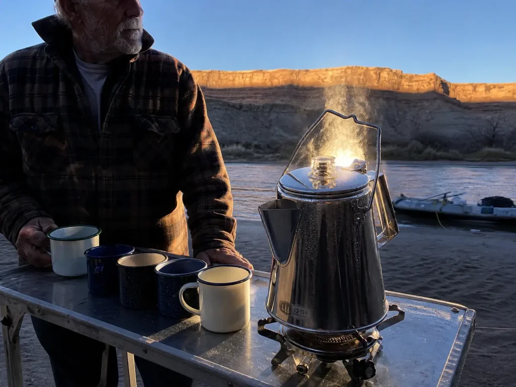 Large stainless percolator brewing camp coffee for a group at a Green River camp