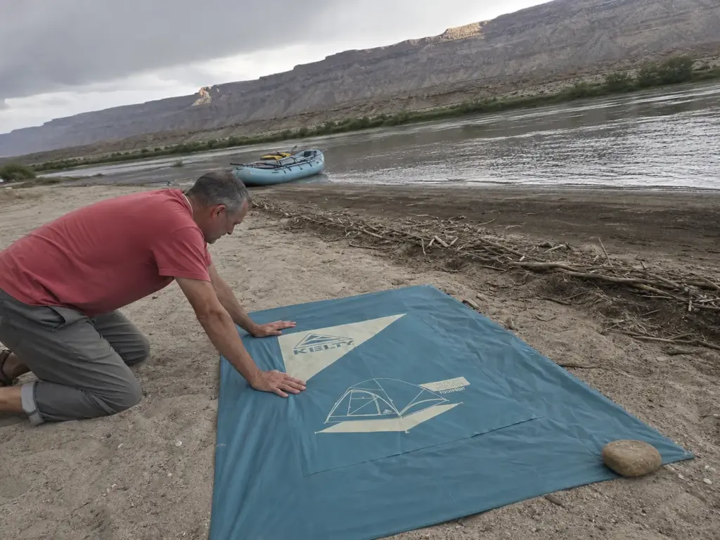 Laying a tent footprint on a sandbar above the high-water line before pitching camp