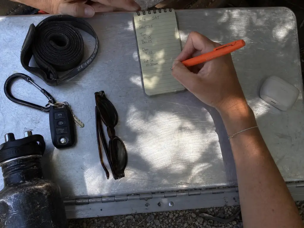 Weatherproof pen and notebook on a dry box next to gear being sorted at the put-in