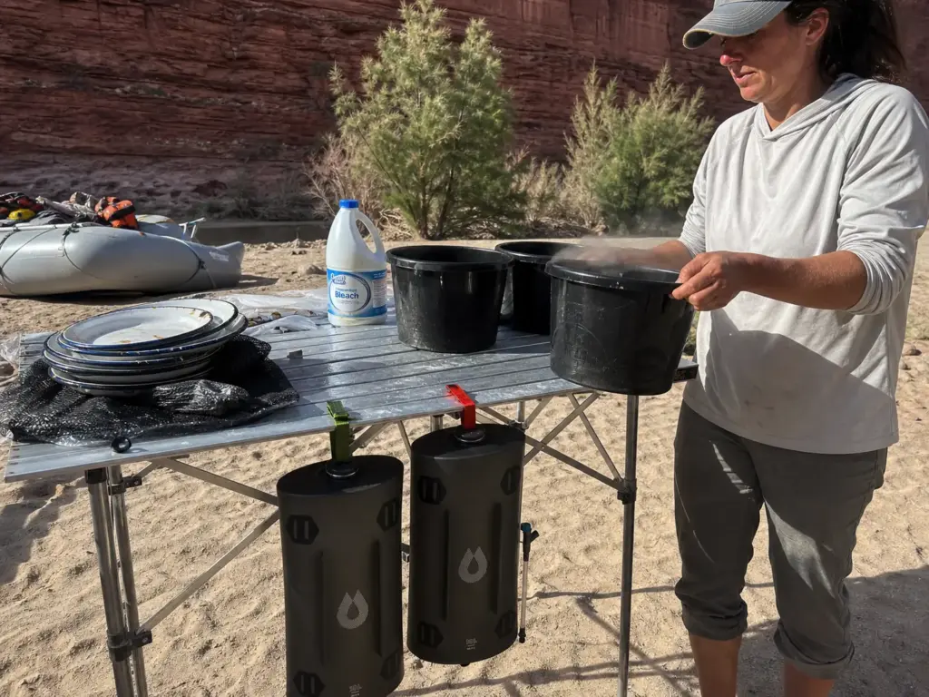 Color-coded cam straps marking treated and untreated water containers at a river camp kitchen