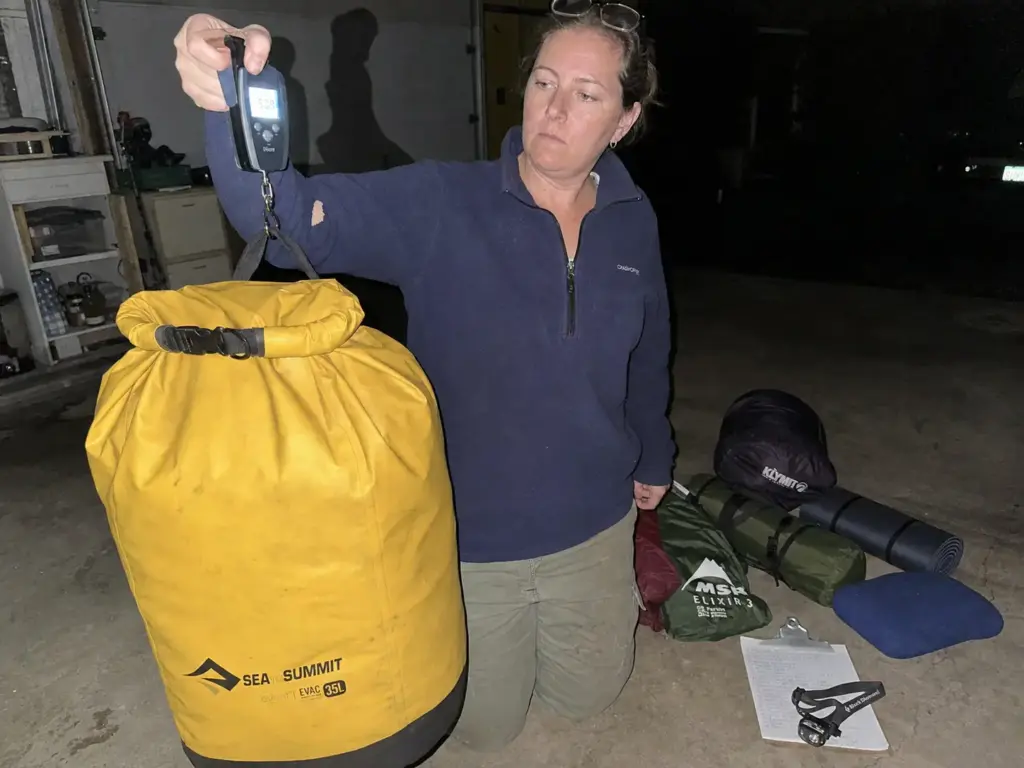 Weighing a packed sleep system dry bag against a river permit personal gear limit at dusk